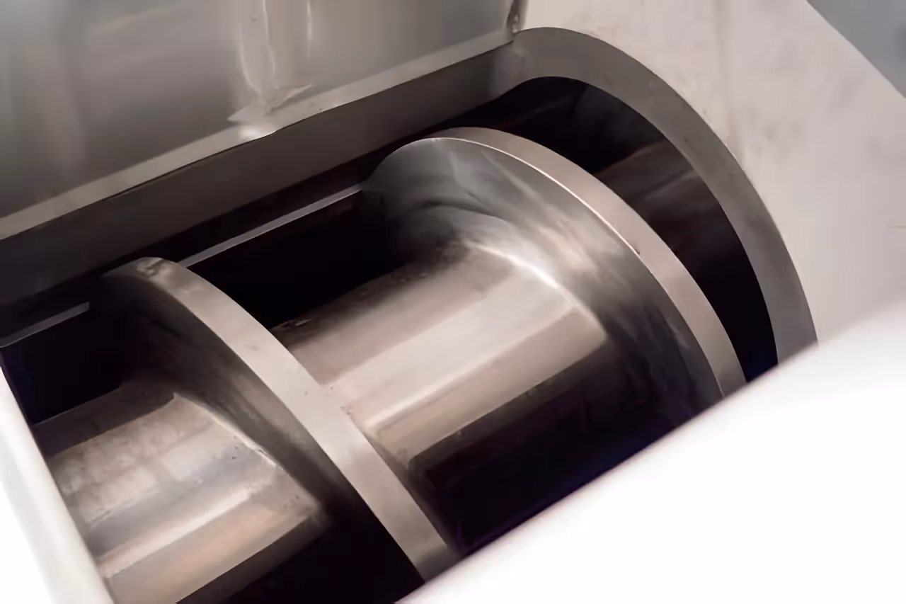 A close-up view of the heavy-duty dewatering screw inside a plastic film squeezer, used for mechanically removing water from recycled film.