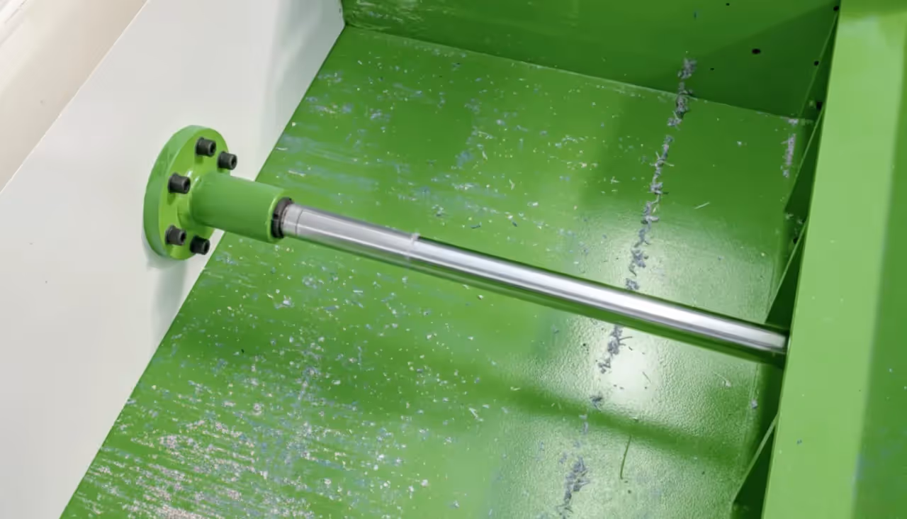 The hydraulic ram and cylinder inside a single-shaft shredder, used to push material into the cutting rotor for efficient processing.